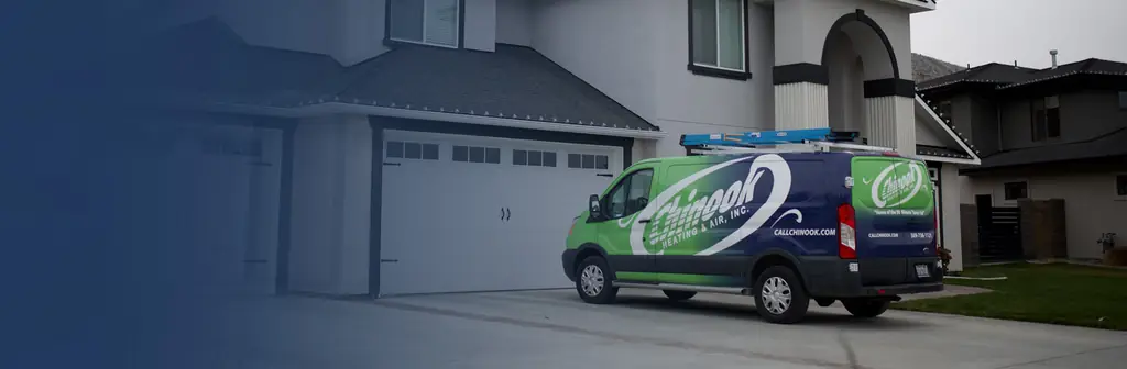 A Chinook van parked on a driveway in front of a house, with Home of the 90 Minute Tune-Up on the rear door